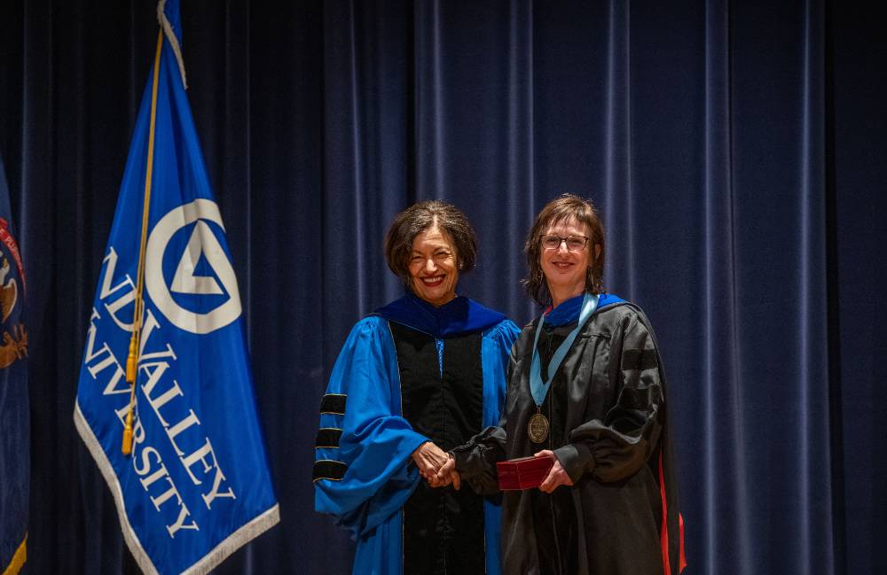 Provost Mili and woman take picture on stage